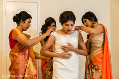 Indian bride being help with her dress.ac Indian bride being help with her dress.ac