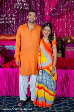 Indian couple in orange sangeet outfits. Indian couple in orange sangeet outfits.