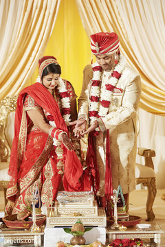 Indian bride and groom pouring rice in to sacred fire Indian bride and groom pouring rice in to sacred fire