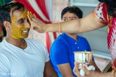 Indian groom is smeared in yellow turmeric paste at his first wedding ceremony ritual haldi ceremony,haldi ritual,pre- wedding celebrations