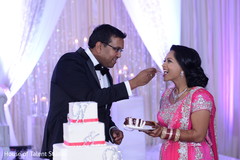 Indian groom giving a piece of cake to bride indian wedding reception,indian wedding cake,indian wedding cake design,indian bride and groom