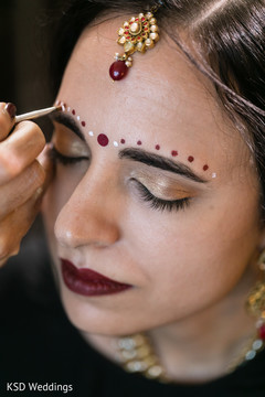 Beautiful indian bride being dolled up for her ceremony indian bridal makeup,indian bride getting ready,indian bride