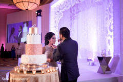 Adorable indian couple's cutting the cake moment indian wedding reception,indian bride and groom,indian wedding cake,indian wedding cake design