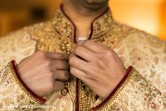Indian groom button up his wedding outfit. Indian groom button up his wedding outfit.