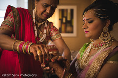 Indian bride being helped with jewelry Indian bride being helped with jewelry