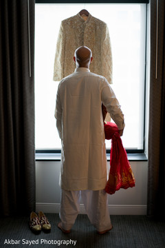 Charming indian groom looking at wedding outfit Charming indian groom looking at wedding outfit