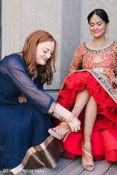 Indian bride being helped with shoes Indian bride being helped with shoes