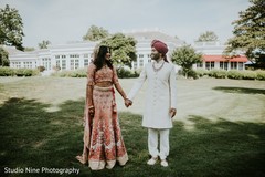 Lovely Indian couple walking outdoors on their wedding traditional outfits. Lovely Indian couple walking outdoors on their wedding traditional outfits.
