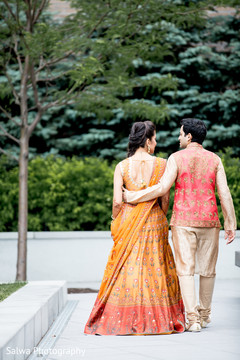 Gorgeous Indian couple walking outdoors with their mehndi outfits. Gorgeous Indian couple walking outdoors with their mehndi outfits.
