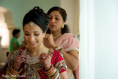 Indian bride being helped with jewelry indian wedding gallery,indian bride getting ready,indian bride fashion,bridal jewelry