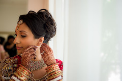 Indian bride putting earrings on indian wedding gallery,indian bride getting ready,indian bride,bridal jewelry