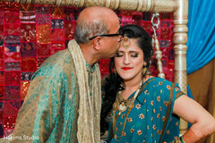 Indian bride being kiss by her father on a pre-wedding celebration.