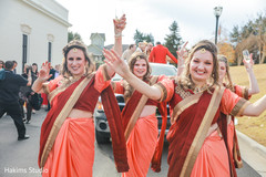 Indian bridesmaids celebrating during the Baraat procession.