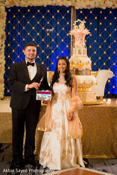 Lovely Indian couple posing with their wedding cake capture. indian bride and groom,indian wedding fashion,indian wedding cake