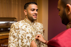 Indian groom getting help to put on his sherani. Indian groom getting help to put on his sherani.