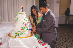 Gorgeous Indian bride and groom cutting cake moment. indian bride and groom,indian wedding reception fashion,indian wedding cake
