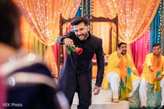 Elegant Indian groom holds a rose and poses for pictures.