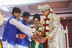 Indian bride and groom given red petals at wedding ritual. Indian bride and groom given red petals at wedding ritual.