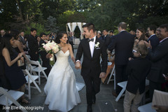 Happy Indian newlyweds leave the ceremony as guests cheer Happy Indian newlyweds leave the ceremony as guests cheer