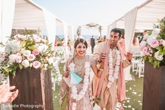 Joyful Indian bride and groom walking out hand in hand from wedding ceremony. Joyful Indian bride and groom walking out hand in hand from wedding ceremony.