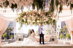 Indian bride and groom hold hands under the floral mandap Indian bride and groom hold hands under the floral mandap