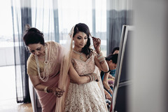 Enchanting Indian bride getting help to put her wedding Ghoonghat veil on. Enchanting Indian bride getting help to put her wedding Ghoonghat veil on.