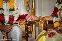 Indian couple hold hands as the ceremony begins Indian couple hold hands as the ceremony begins