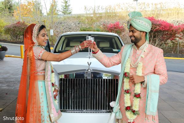 Indian couple making a toast in front of their ride after the ceremony