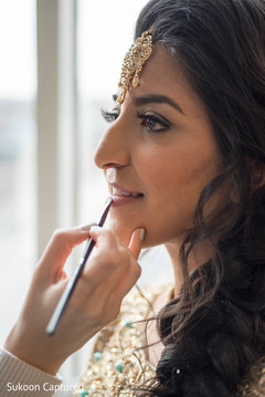 Indian bride getting makeup last touch ups for her wedding reception. Indian bride getting makeup last touch ups for her wedding reception.
