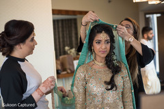 Indian bride getting help to put her wedding ghunghat veil on.