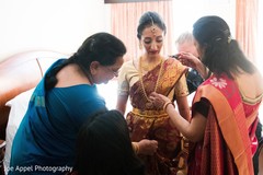 Indian bride being assisted with the beautiful sari and bridal jewelry Indian bride being assisted with the beautiful sari and bridal jewelry