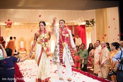 Joyful Indian couple hold hands as the Indian wedding ceremony ends Joyful Indian couple hold hands as the Indian wedding ceremony ends
