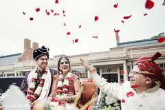 Cheerful Indian couple smile as a special guest throws rose petals Cheerful Indian couple smile as a special guest throws rose petals