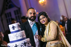 Adorable indian newlyweds next to their cake Adorable indian newlyweds next to their cake