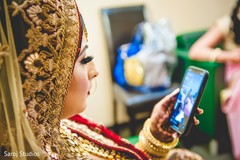 Indian bride checking her phone as she gets ready Indian bride checking her phone as she gets ready
