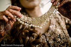 Indian bride putting her Polki necklace choker. Indian bride putting her Polki necklace choker.