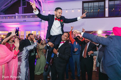 Indian groom being lifted up during reception celebration. Indian groom being lifted up during reception celebration.