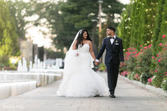 Indian bride and groom holding hands as they walk Indian bride and groom holding hands as they walk