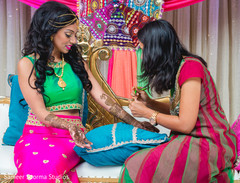 Dazzling Indian bride being assisted by mehndi artist Dazzling Indian bride being assisted by mehndi artist
