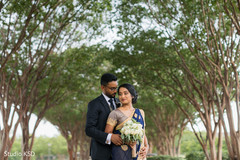 Indian bride posing with her husband by the trees Indian bride posing with her husband by the trees