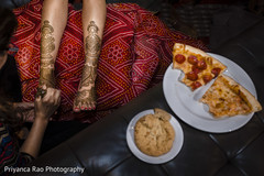 Indian bride being assisted with the mehndi design Indian bride being assisted with the mehndi design
