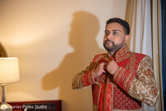 Indian groom putting his sherwani on. Indian groom putting his sherwani on.