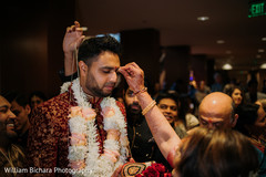 Indian groom holding coconut and getting the red dot on forehead. Indian groom holding coconut and getting the red dot on forehead.