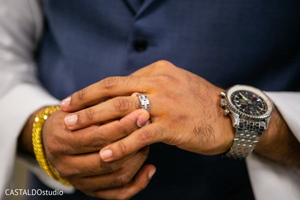 Indian groom putting his jewelry on.