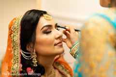 Indian bride being assisted by makeup artist Indian bride being assisted by makeup artist
