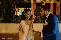 Indian bride and groom sharing a slice of cake Indian bride and groom sharing a slice of cake