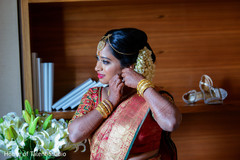 Indian bride putting her earrings on. Indian bride putting her earrings on.