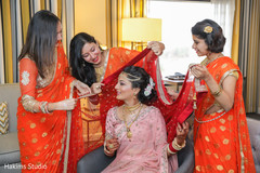 Indian bride being helped to put her traditional red Ghoonghat. Indian bride being helped to put her traditional red Ghoonghat.
