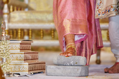 Indian bride climbing over a stone at ceremony ritual. Indian bride climbing over a stone at ceremony ritual.