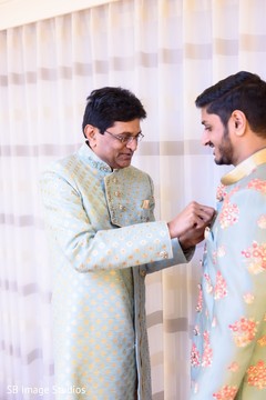 Indian groom's relative helping putting on his sherwani. Indian groom's relative helping putting on his sherwani.